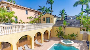 Ein Poolbereich mit Liegestühlen, einem Whirlpool und einer überdachten Terrasse mit Bögen.