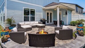Eine Terrasse mit Korbmöbeln, einer Feuerstelle und Kübelpflanzen.