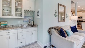 Eine Küche mit weißen Schränken, einer Marmorarbeitsplatte und einem Essbereich mit einem weißen Sofa und Kissen.