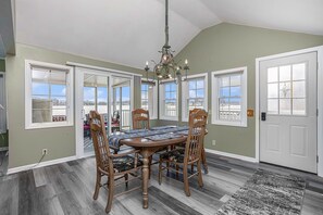 A dining room with a wooden table, chairs, and a chandelier.