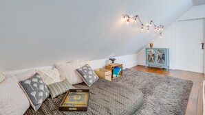 A cozy attic bedroom with a sloped ceiling, a patterned rug, and a variety of pillows and blankets. - Journey/Retreat ready! Private swimming hole, just 2hrs from Boston (Corinth)