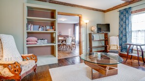 A living room with a glass coffee table, wooden bookshelves, a television, and a cozy chair. - Journey/Retreat ready! Private swimming hole, just 2hrs from Boston (Corinth)