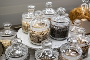 A collection of glass jars with lids, containing various grains and seeds, displayed on a marble surface.