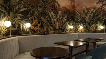 Un restaurant doté d’un espace où l’on peut s’asseoir, avec des bancs rembourrés et des tables rondes, le tout éclairé par des lampes suspendues au design moderne.