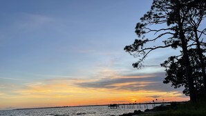 A beach with a pier extending into the water, surrounded by trees and a clear sky. - Eastpoint on the  Bay - private Beach, pool, sunsets (Eastpoint)
