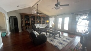 A spacious living room with hardwood flooring, a leather sofa, a coffee table, and a ceiling fan. - Eastpoint on the  Bay - private Beach, pool, sunsets (Eastpoint)