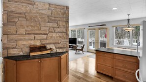 Una cocina moderna con protector contra salpicaduras de pared de piedra, armarios de madera y una isla grande.