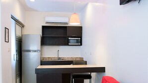 A compact kitchen with a refrigerator, microwave, and pendant light.