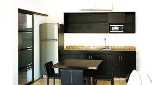 A compact kitchen with a refrigerator, microwave, and a dining table with chairs.