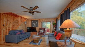 A wooden interior with a staircase, a television, a sofa, a coffee table, and a lamp. - BASE CAMP LA CONCEPTION (La Conception)