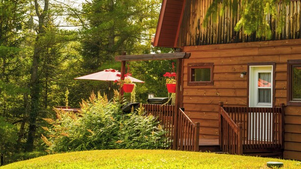 A wooden cabin with a deck, surrounded by lush greenery and trees. - BASE CAMP LA CONCEPTION (La Conception)