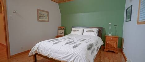 A bedroom with a wooden bed, green walls, and a ceiling fan.