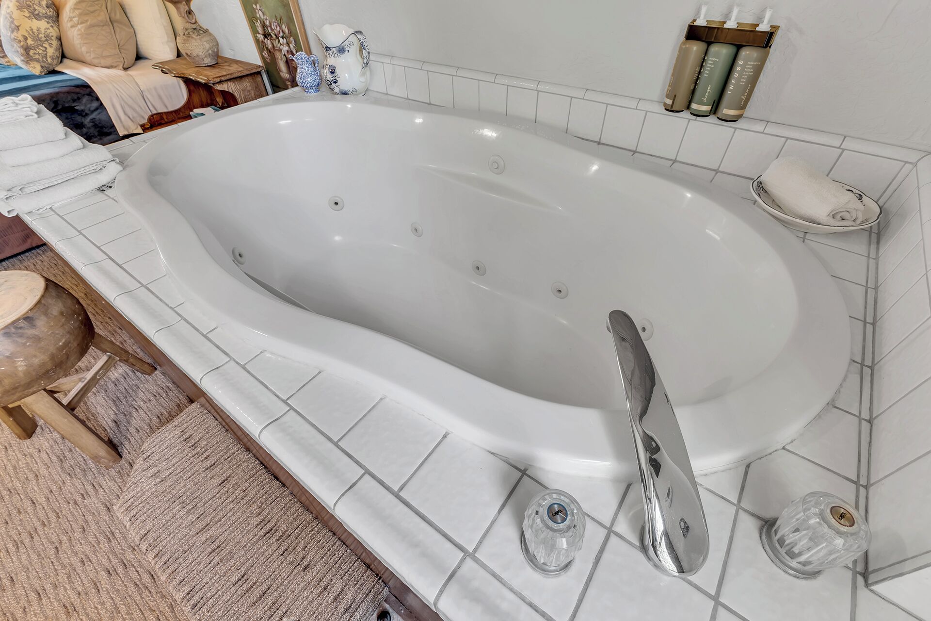Une grande baignoire de forme ovale, dotée d’un robinet moderne et d’une douchette à main.