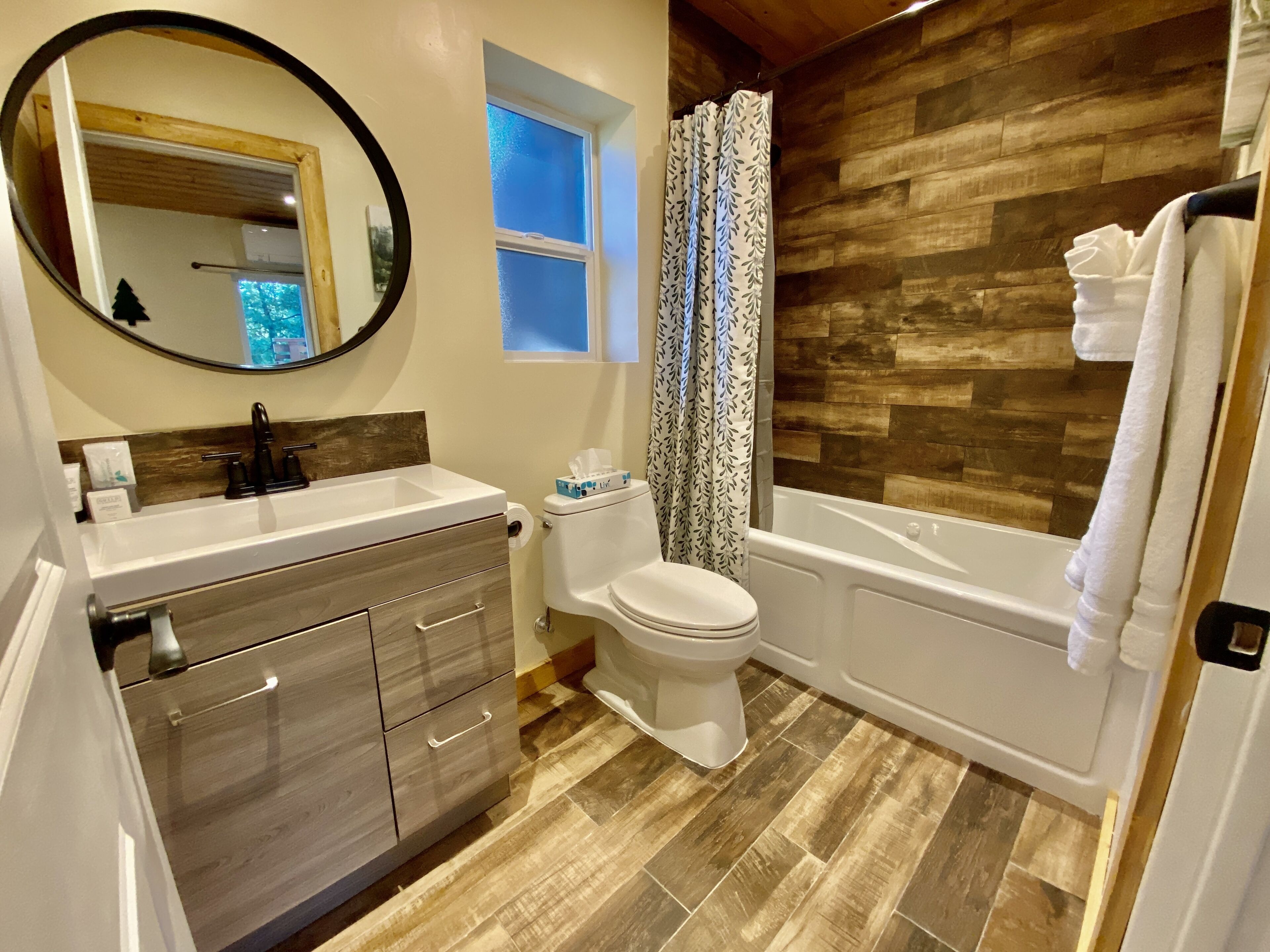 A bathroom with a wooden floor, a white sink, a toilet, and a bathtub.