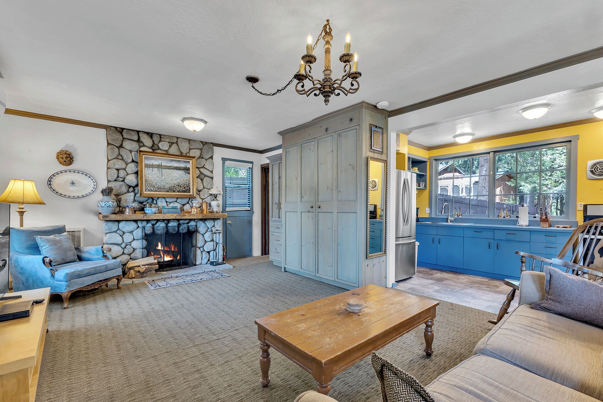 A spacious living room with a fireplace, a dining area, and a kitchen with blue cabinets.