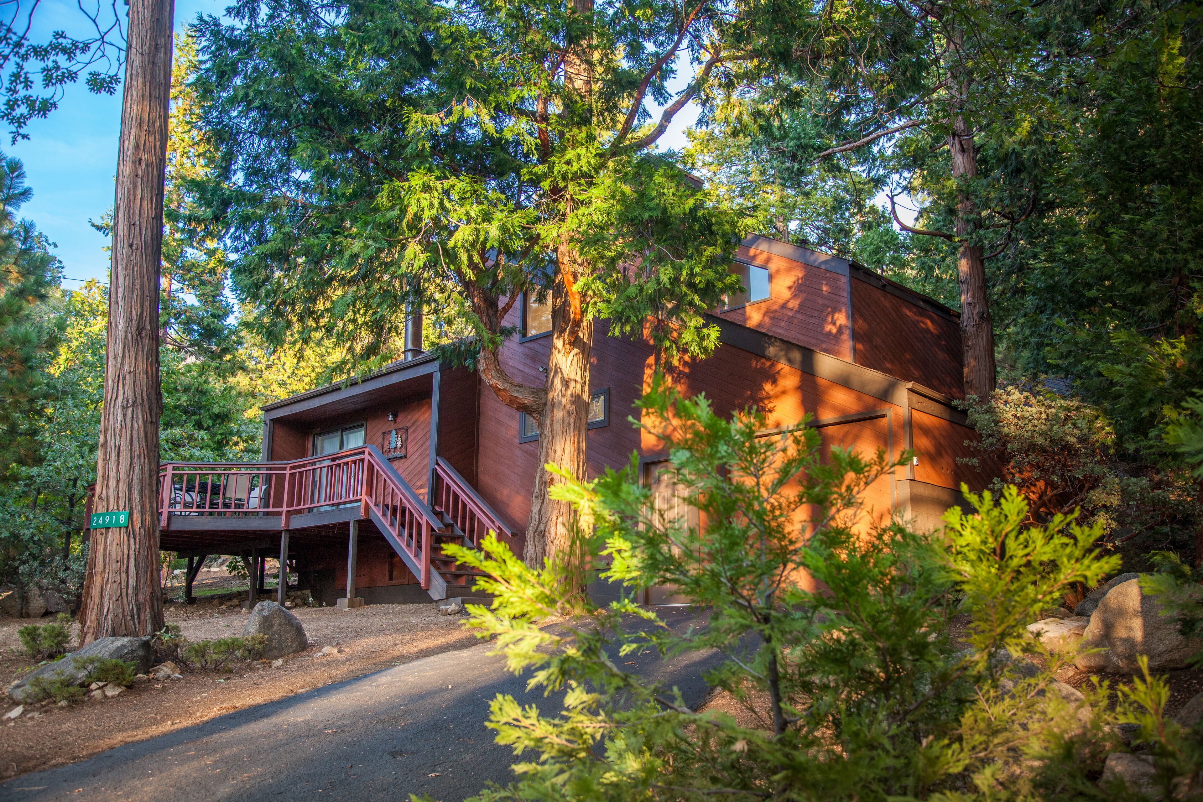 A cabin with a wooden exterior, a deck, and a staircase leading to an upper level.