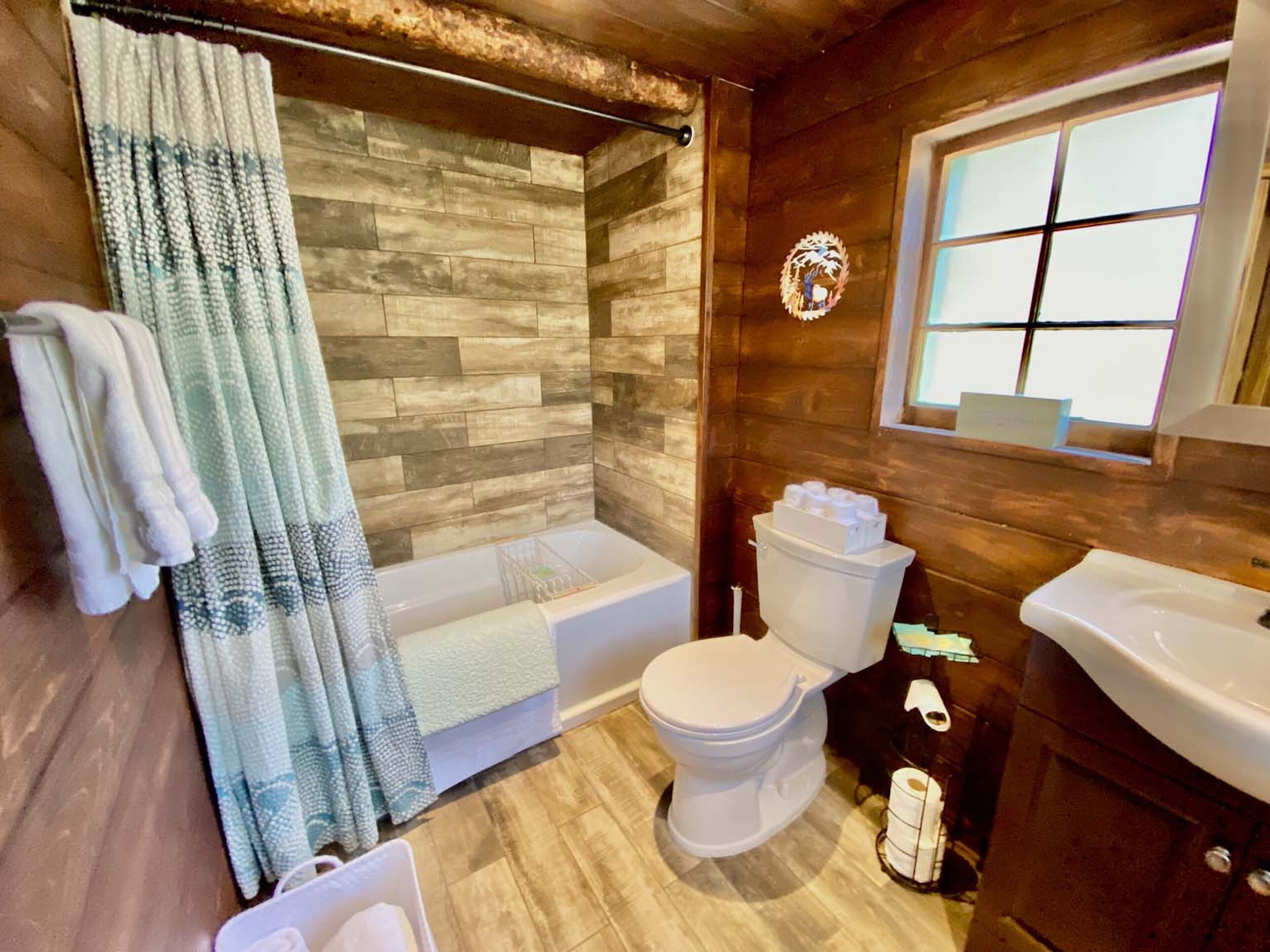 A bathroom with a wooden wall, a bathtub, a toilet, and a sink.