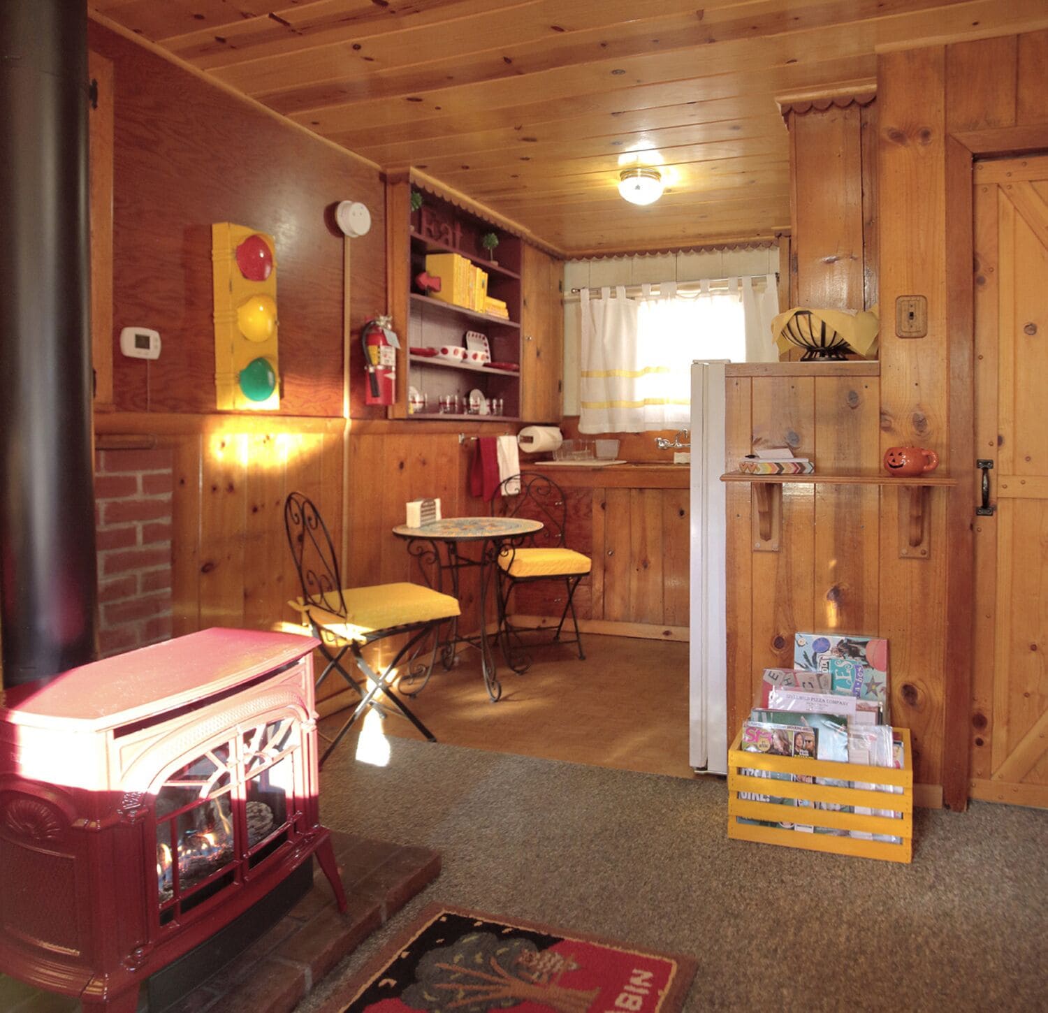 Un intérieur de chalet chaleureux avec une cheminée, des murs en bois, un coin repas et une cuisine.