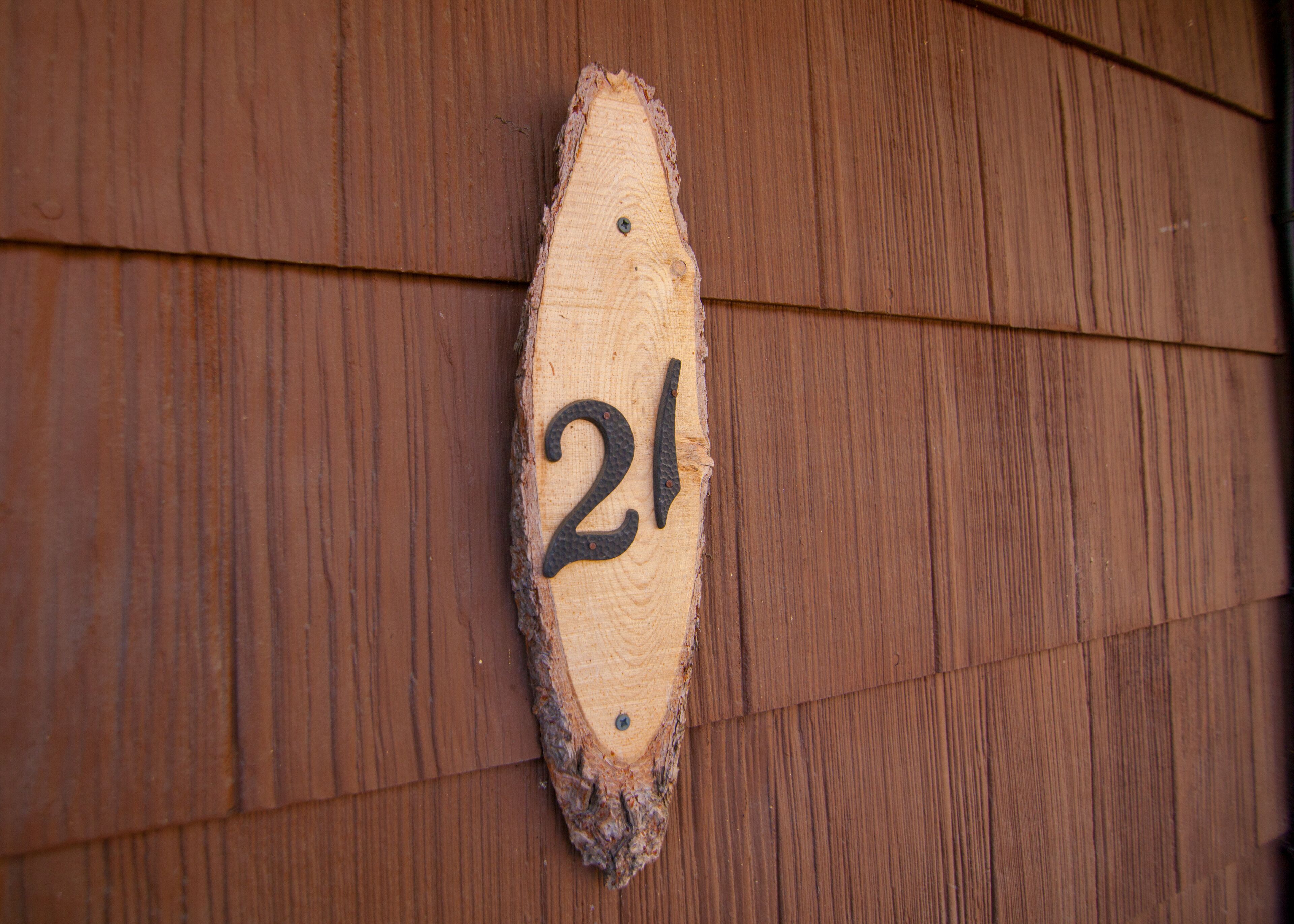 A wooden number plaque with the number 21 on a wooden wall.