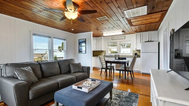 A modern living room with a gray sofa, a coffee table, and a dining area with chairs.