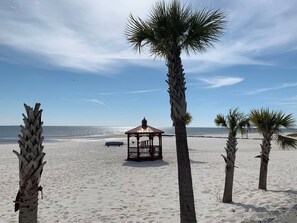 Ein Strand mit einem Pavillon und Palmen.