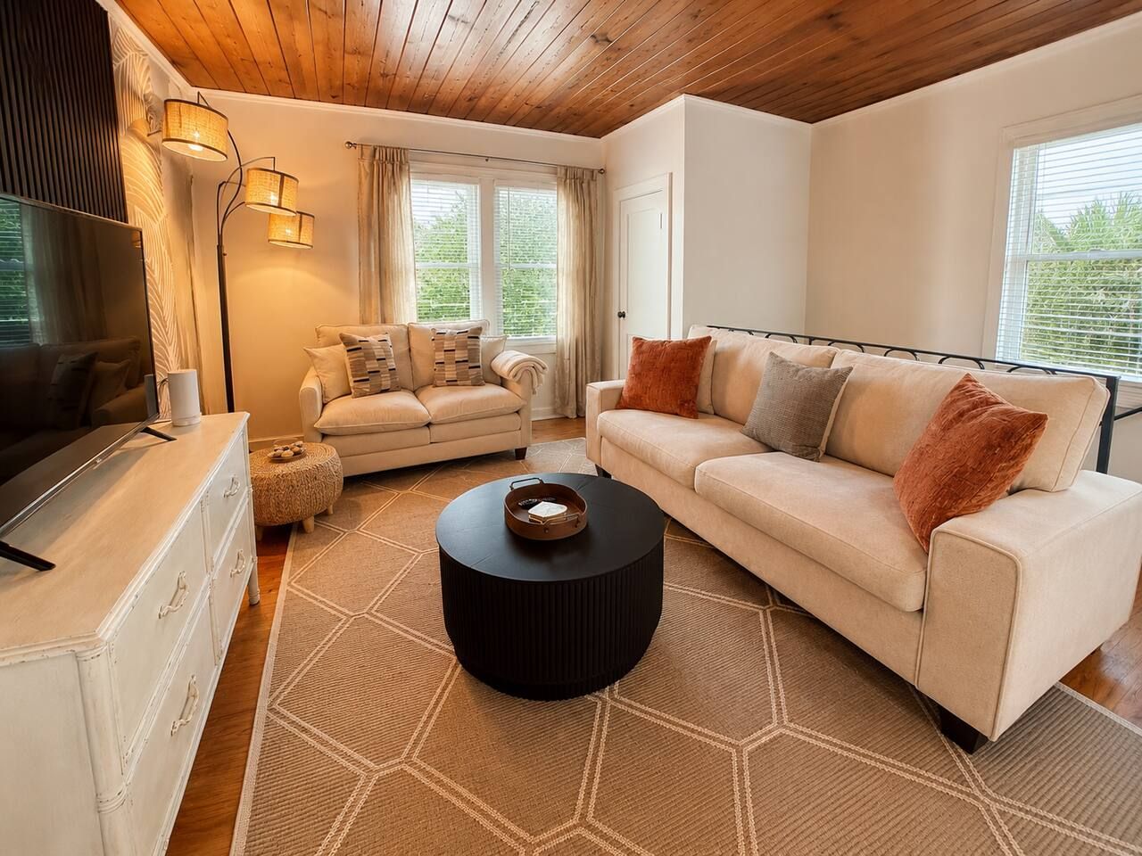 Un salon moderne avec un canapé, une table basse et un téléviseur posé sur une commode.