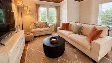 Un salon moderne avec un canapé, une table basse et un téléviseur posé sur une commode.