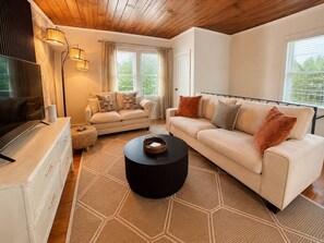 Ein modernes Wohnzimmer mit einer Couch, einem Couchtisch und einem Fernseher auf einer Kommode.