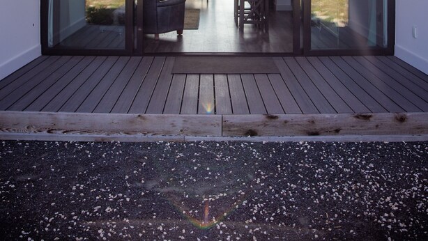 Ein modernes Haus mit einer großen Glasdoor, die auf eine Terrasse mit Essbereich führt.