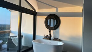 Ein modernes Badezimmer mit einer freistehenden Badewanne, einem runden Spiegel und einer Duschkabine.