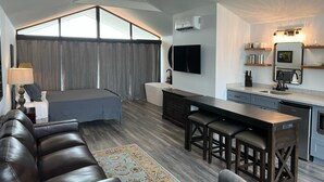 Eine moderne Wohnung mit Schlafzimmer im Loft-Stil, einer Küche mit Barhocker und einem Essbereich.