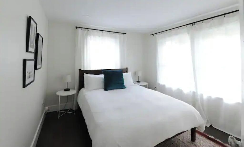 Une chambre à coucher bien rangée, avec un grand lit, deux tables de chevet et une petite table d’appoint.