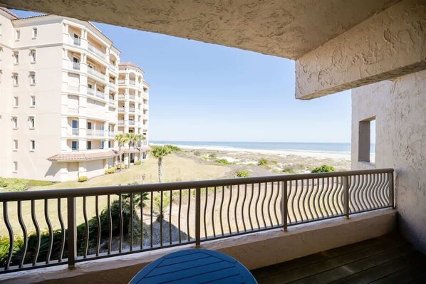 A balcony with a view of a beach and a multi-story building. - Sandcastle Court #275 -Kitchen (Nassau County)