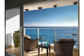 Enjoy the ocean view from this balcony with a comfortable seating area.