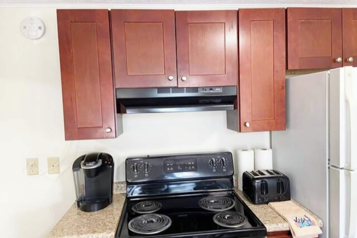 A compact kitchen with a stove, toaster, and refrigerator.