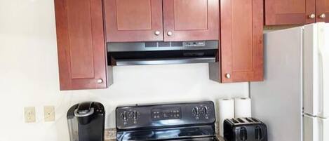 A compact kitchen with a stove, toaster, and refrigerator.