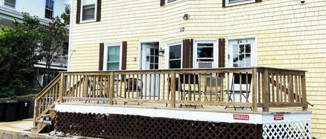 A two-story building with a wooden deck and a white fence.
