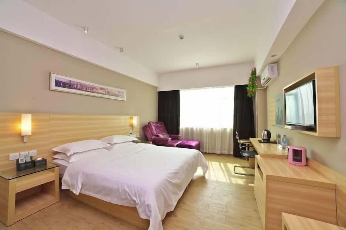 Une chambre d’hôtel avec un lit, un bureau, une chaise, une télévision et une fenêtre.
