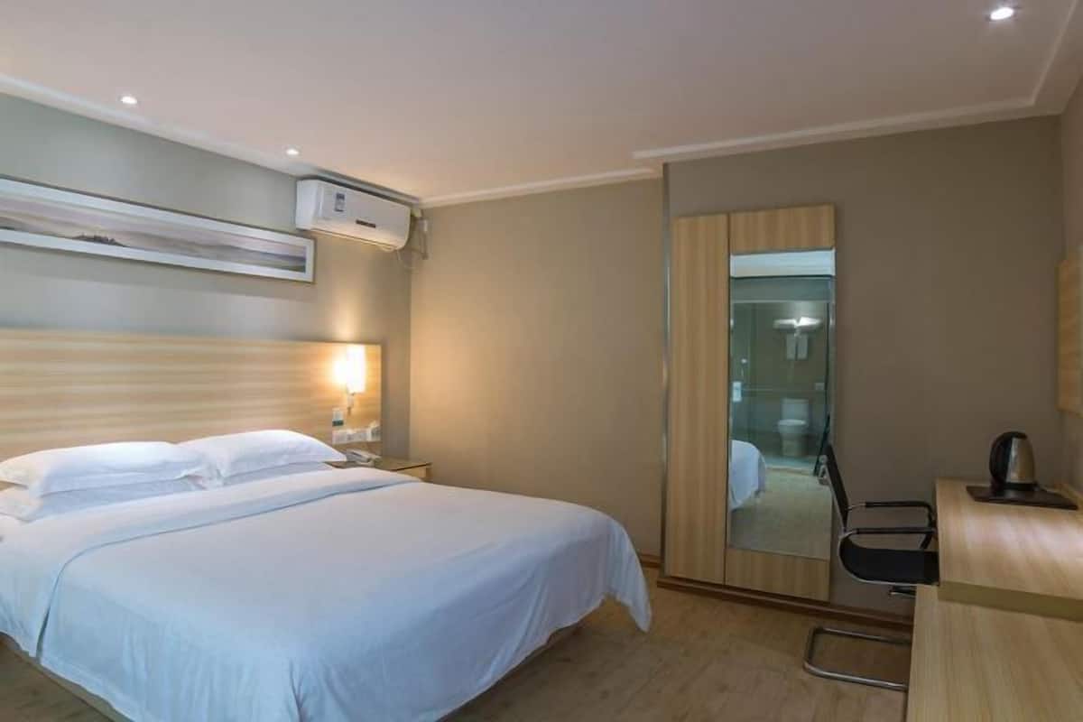 Une chambre d’hôtel avec un lit, une table de chevet, une lampe et un miroir.