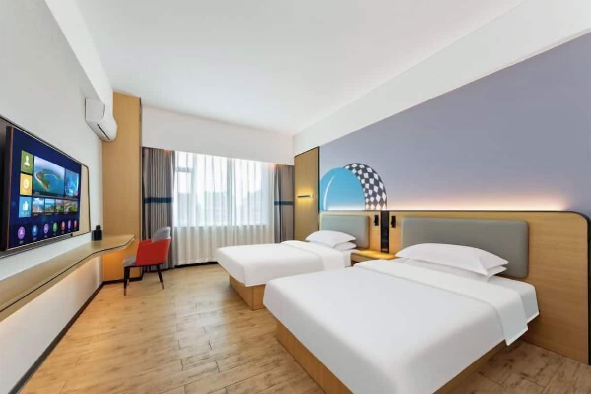 Une chambre d’hôtel avec deux lits, une télévision, un bureau et une chaise.
