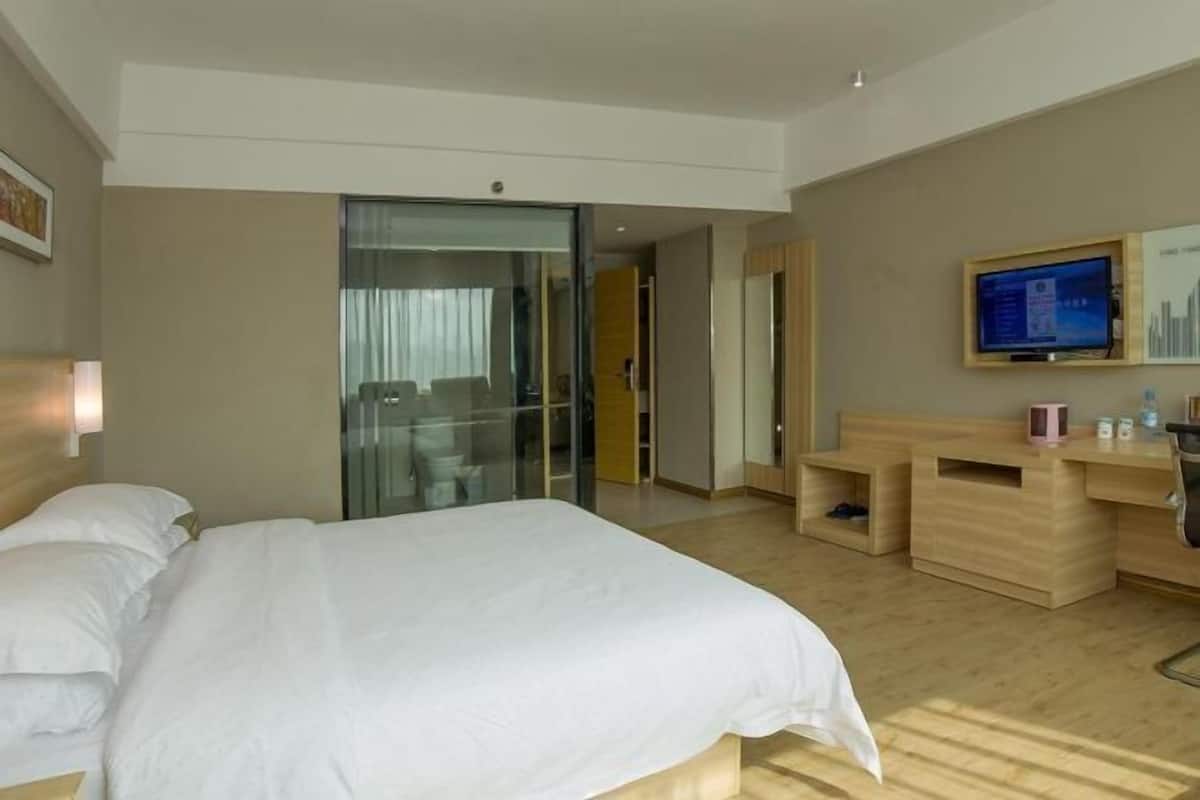 Une chambre d’hôtel équipée d’un lit, d’un bureau, d’une télévision et d’une porte coulissante donnant accès à la salle de bain.
