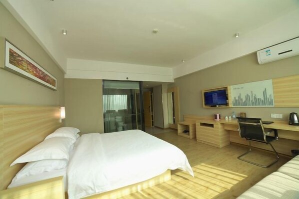 Quarto de hotel com cama, escrivaninha, cadeira, televisão e obra de arte na parede.