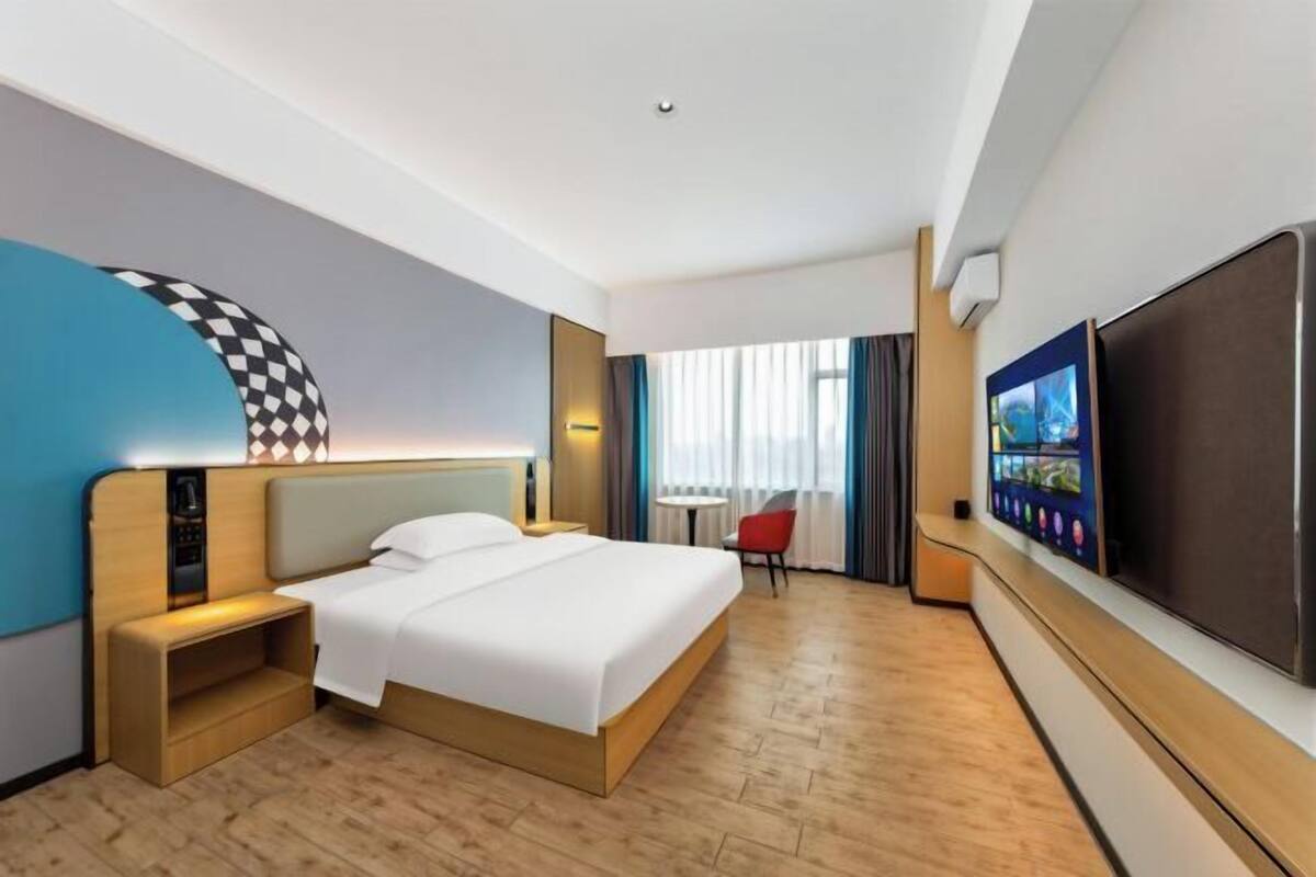 Une chambre d’hôtel comprenant un lit, une table de chevet, une télévision et un petit coin salon.