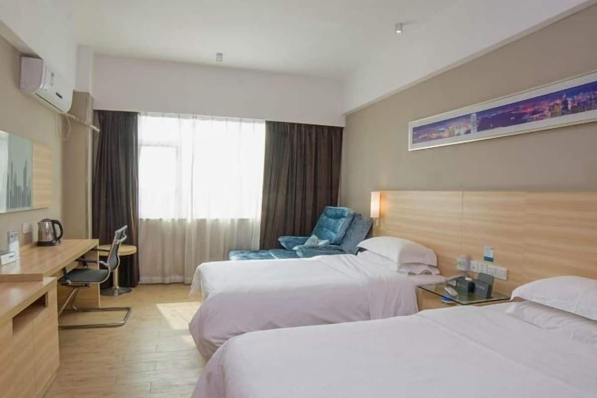 Une chambre d’hôtel avec deux lits, un bureau avec une chaise, une machine à café, une chaise et un tableau au mur.