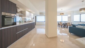 A modern kitchen with a built-in oven and a dining area with a table and chairs. - KYPSELI PLATINUM (Athens)