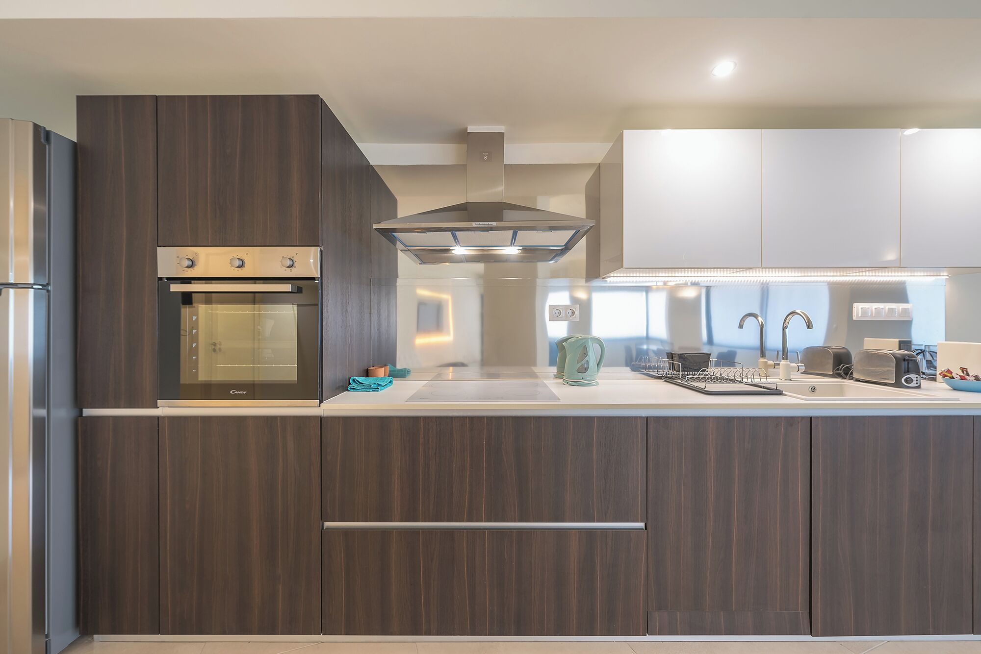 A modern kitchen with dark wood cabinetry, stainless steel appliances, and a central island with a sink and countertop.