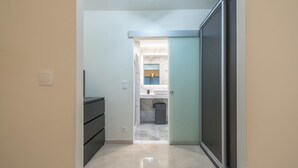 A narrow hallway leading to a bathroom with a toilet, sink, and mirror. - KYPSELI PLATINUM (Athens)