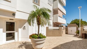 A building with a large planter with a palm tree and red flowers in front of a white door labeled "PORTAL 3". - Apartment in Rota-Cádiz, new and modern near the beach. (Rota)