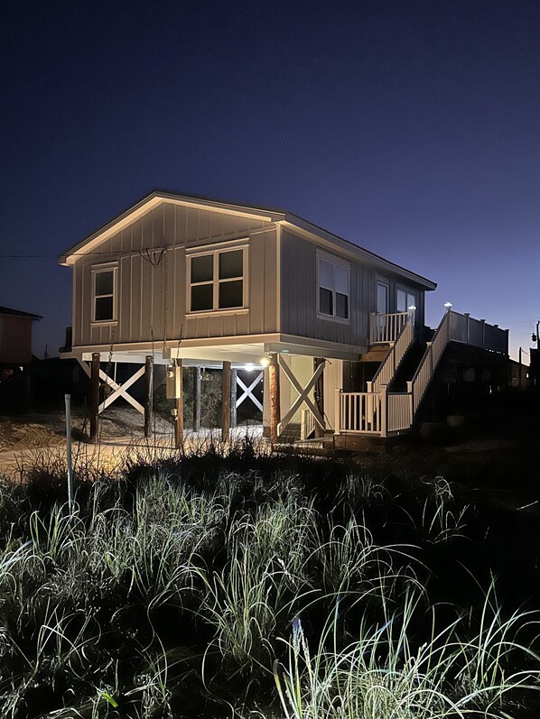 A two-story house with a balcony, wooden railings, and a staircase leading to the upper level.