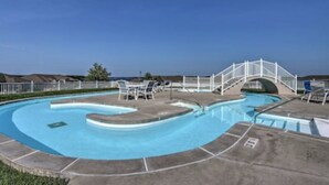 A swimming pool with a curved design, a white bridge, and lounge chairs. - Updated Lands End Upscale Condo - Sleeps 9 (Osage Beach)